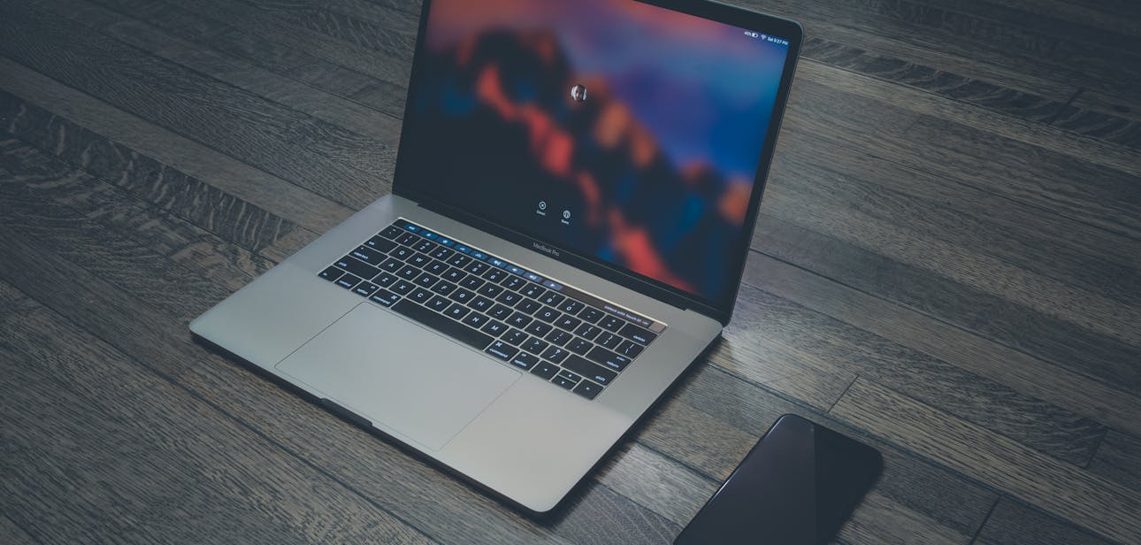 A sleek laptop and smartphone placed on wooden flooring, showcasing contemporary technology.