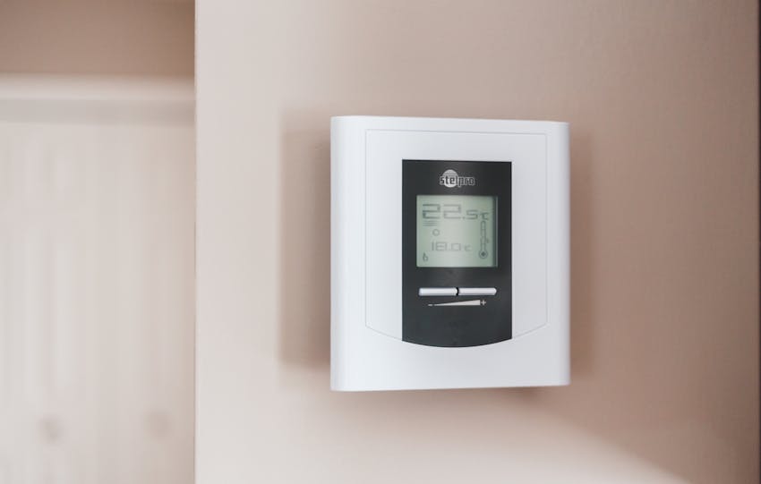 Close-up of a modern digital thermostat mounted on a wall, displaying temperature settings in Celsius.