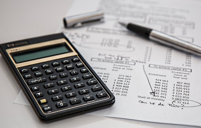 Close-up of financial documents with calculator and pen, ideal for business management themes.