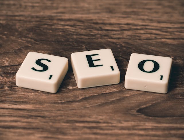 Scrabble tiles spelling 'SEO' on a wooden surface. Ideal for digital marketing themes.